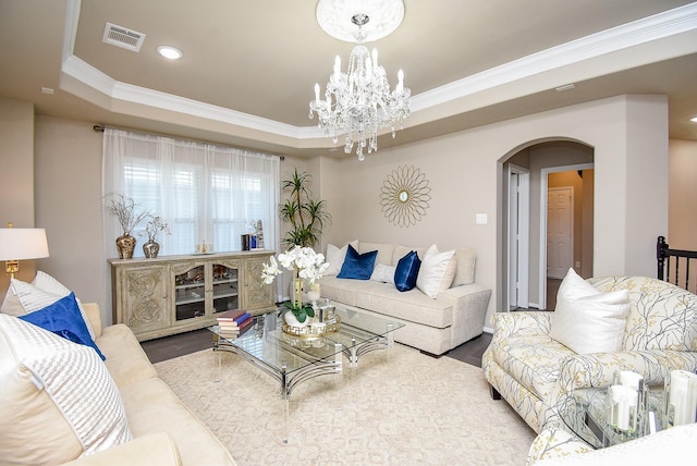 living room with a tray ceiling, arched walkways, crown molding, and wood finished floors