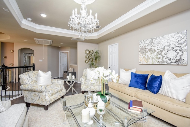 living room featuring a raised ceiling, attic access, and crown molding