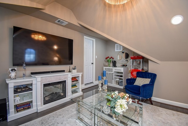 living room with lofted ceiling, wood finished floors, visible vents, and baseboards