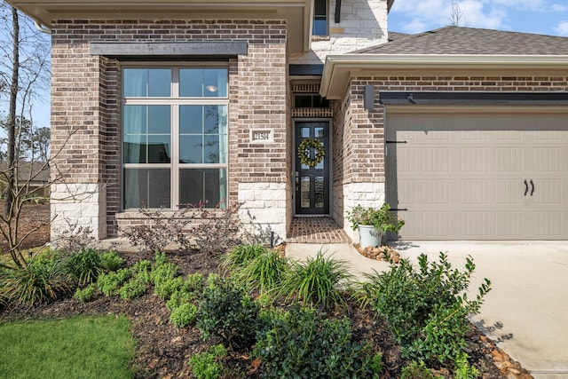 entrance to property featuring brick siding, an attached garage, and roof with shingles