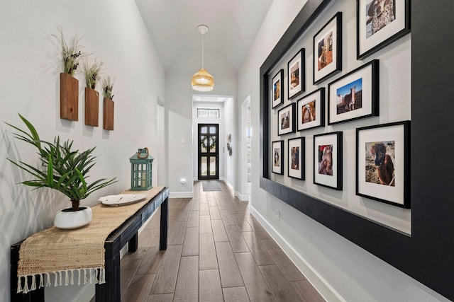 hallway with dark wood-style floors, lofted ceiling, and baseboards