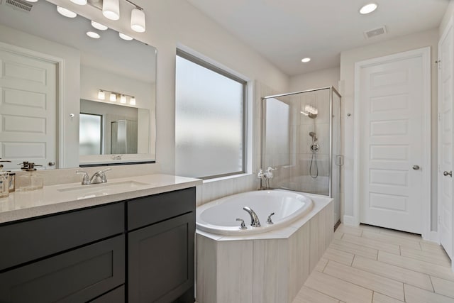 bathroom featuring a garden tub, vanity, a shower stall, and visible vents