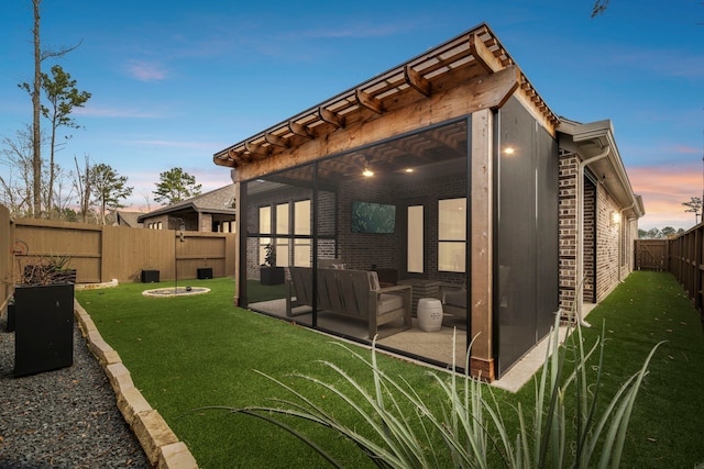 back of property at dusk featuring a yard, a fenced backyard, a patio, and brick siding