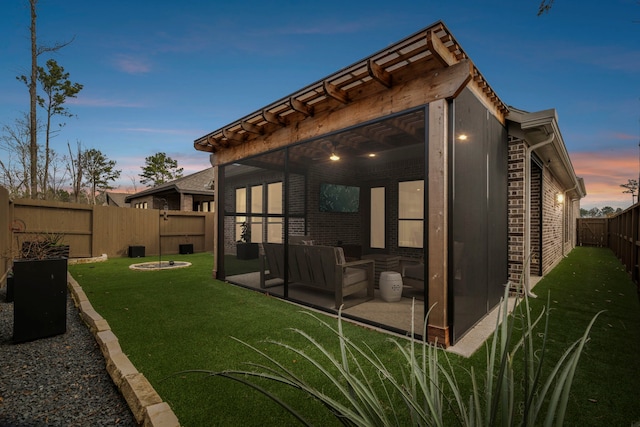 back of property featuring a fenced backyard, a patio, a lawn, and brick siding