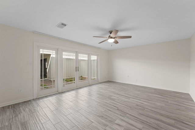 spare room featuring french doors, visible vents, light wood-style floors, ceiling fan, and baseboards