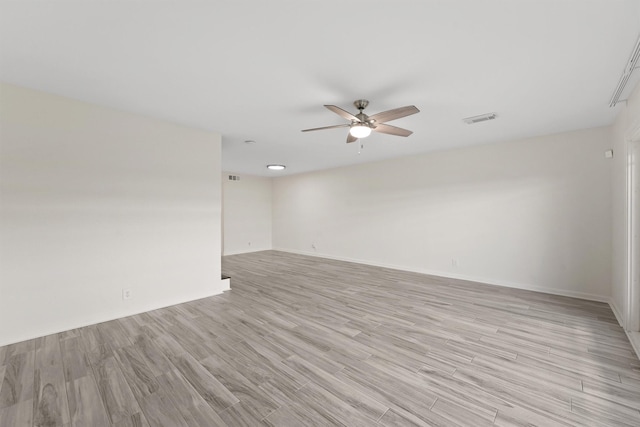 spare room featuring light wood finished floors, ceiling fan, visible vents, and baseboards