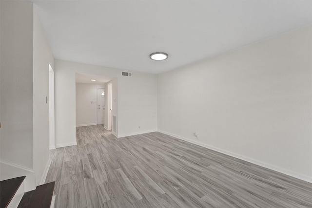 spare room featuring baseboards, visible vents, and light wood finished floors