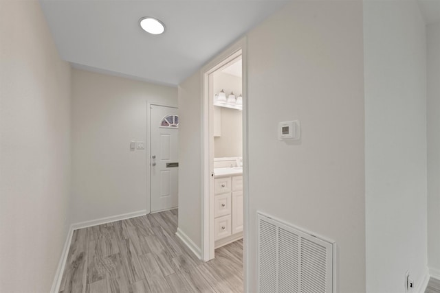 hallway featuring baseboards, visible vents, and light wood-style floors