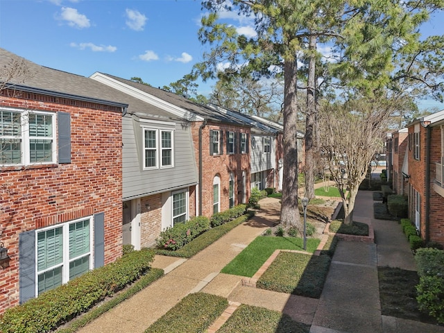 view of side of home with brick siding and a shingled roof