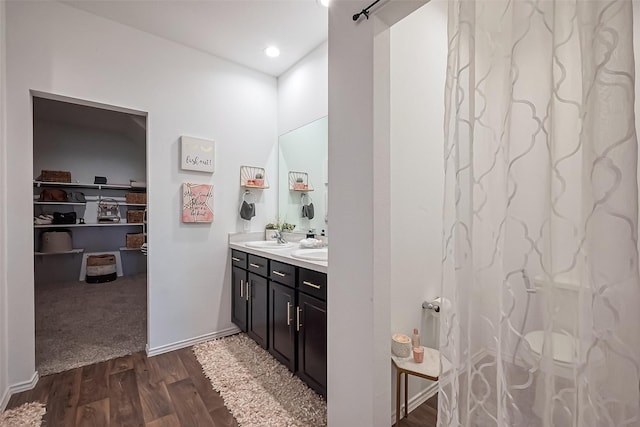 full bathroom with a sink, wood finished floors, recessed lighting, double vanity, and baseboards