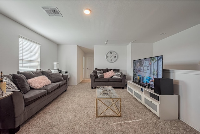 carpeted living room featuring visible vents and attic access