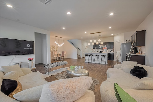 living room with visible vents, stairs, recessed lighting, an inviting chandelier, and dark wood-style flooring