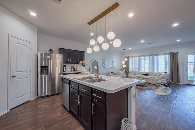 kitchen with a sink, stainless steel appliances, dark wood-type flooring, and light countertops