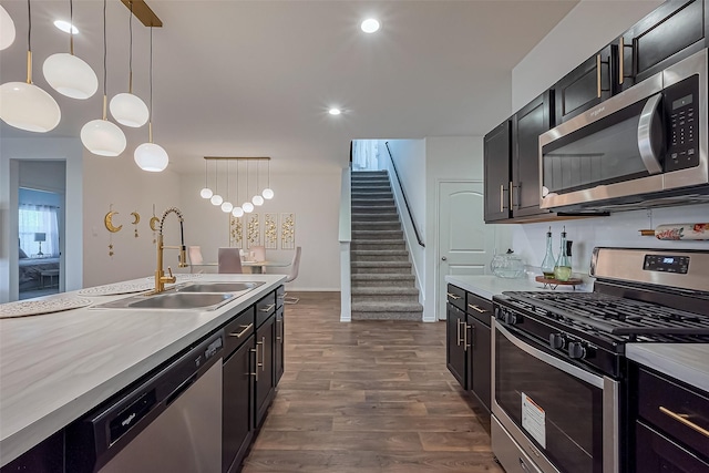 kitchen featuring dark wood-style flooring, a sink, light countertops, appliances with stainless steel finishes, and pendant lighting