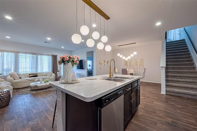 kitchen with an island with sink, a sink, stainless steel dishwasher, open floor plan, and dark wood finished floors