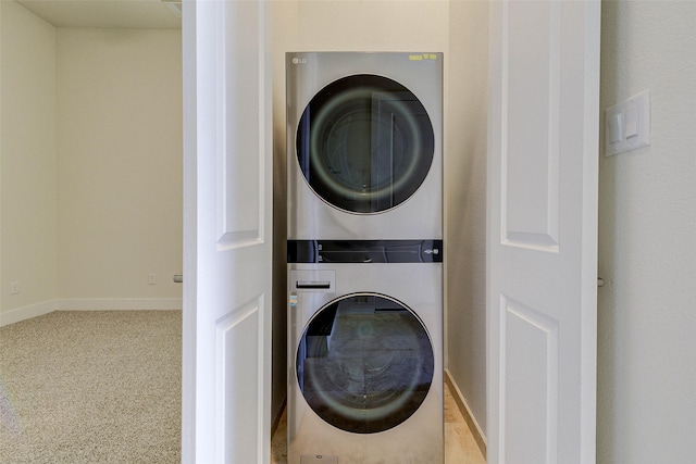 laundry room with baseboards, carpet, stacked washer and clothes dryer, and laundry area