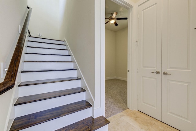 stairway with carpet, tile patterned floors, and a ceiling fan