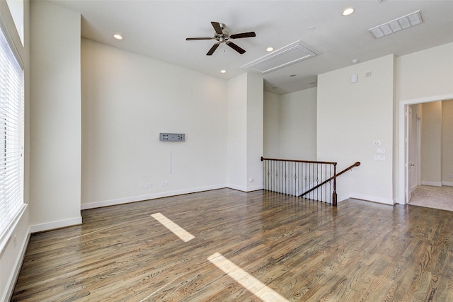 unfurnished room with ceiling fan, visible vents, attic access, and wood finished floors