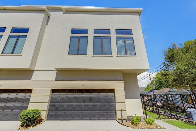 view of front of home with an attached garage, fence, driveway, and stucco siding