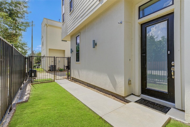 view of exterior entry featuring stucco siding, a lawn, and fence