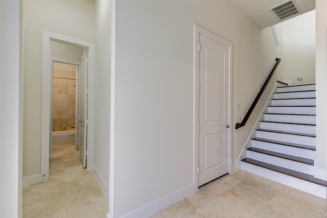 stairs with tile patterned floors, visible vents, and baseboards