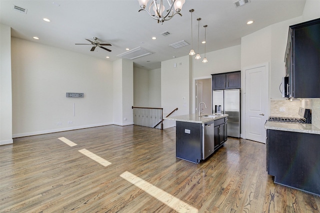 kitchen featuring visible vents, ceiling fan with notable chandelier, a sink, open floor plan, and stainless steel appliances