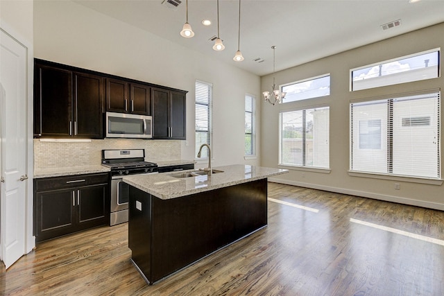 kitchen featuring visible vents, light wood-style flooring, a notable chandelier, stainless steel appliances, and a sink