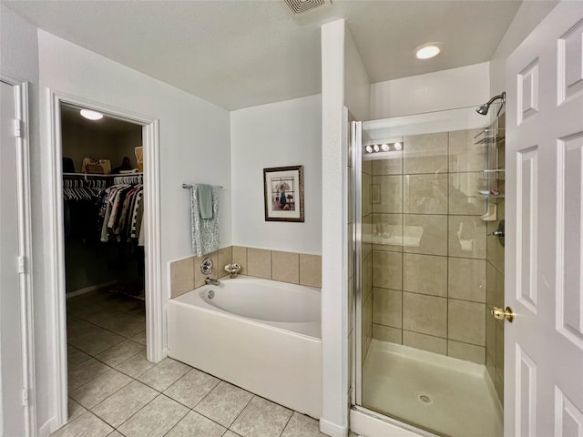 full bathroom with tile patterned flooring, visible vents, a spacious closet, a bath, and a stall shower