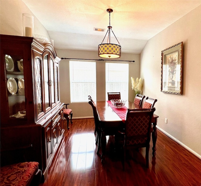 dining room featuring vaulted ceiling, visible vents, dark wood finished floors, and baseboards