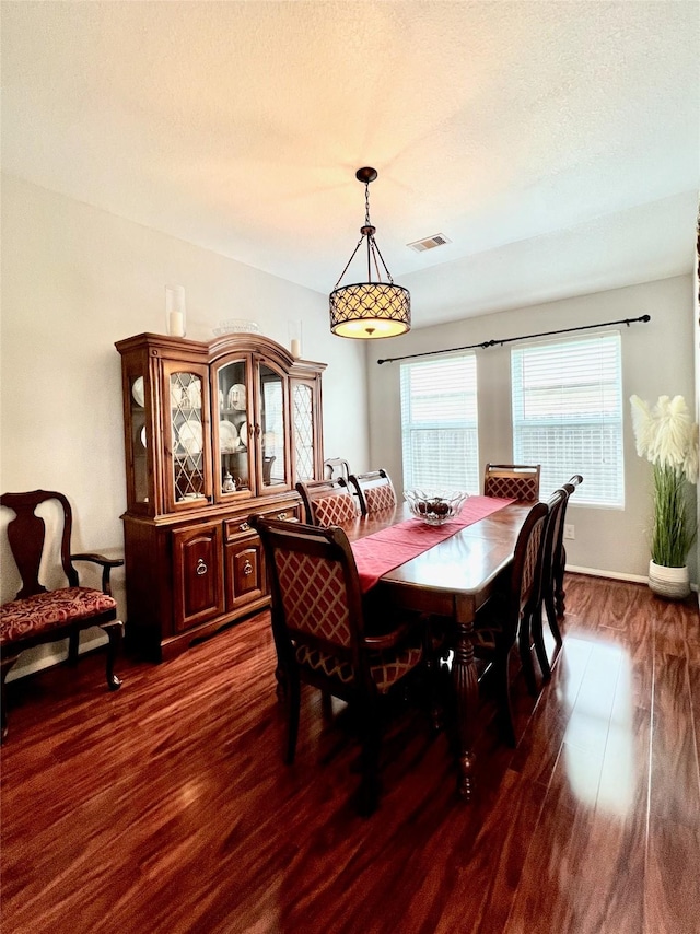 dining space with dark wood-type flooring, visible vents, and a textured ceiling