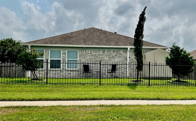 exterior space with a front yard, stone siding, roof with shingles, and fence