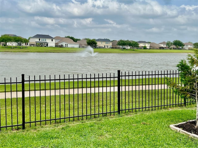 view of yard featuring a water view, fence, and a residential view