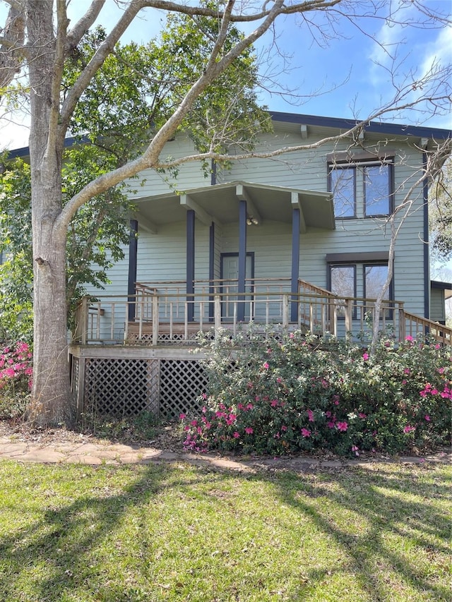 rear view of house featuring covered porch and a yard