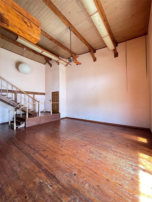 empty room featuring ceiling fan, wooden ceiling, hardwood / wood-style flooring, stairway, and beam ceiling