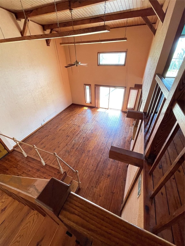 unfurnished living room with a textured wall, hardwood / wood-style floors, wooden ceiling, and beam ceiling