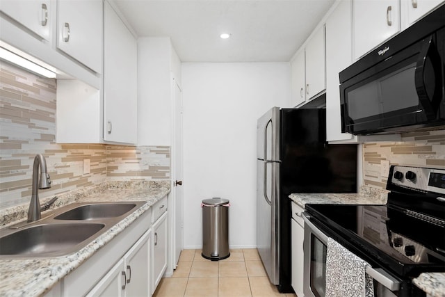 kitchen with light tile patterned floors, black microwave, stainless steel electric stove, white cabinetry, and a sink