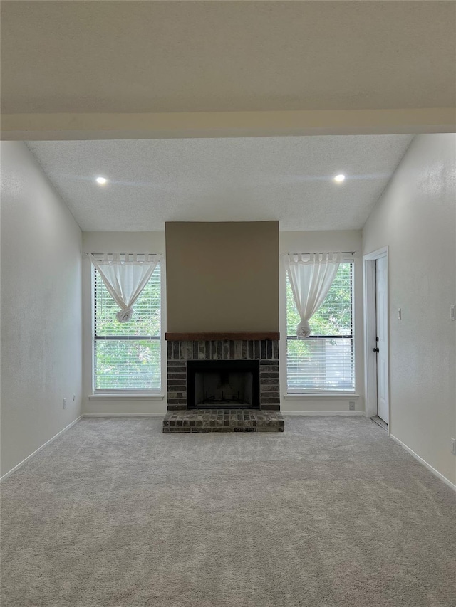 unfurnished living room with a wealth of natural light, a brick fireplace, and carpet