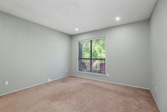 empty room featuring recessed lighting, light carpet, a textured ceiling, and baseboards