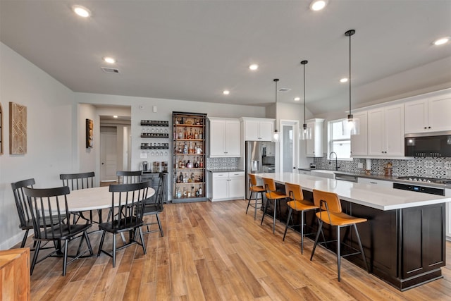 kitchen featuring a spacious island, appliances with stainless steel finishes, white cabinetry, and a kitchen bar