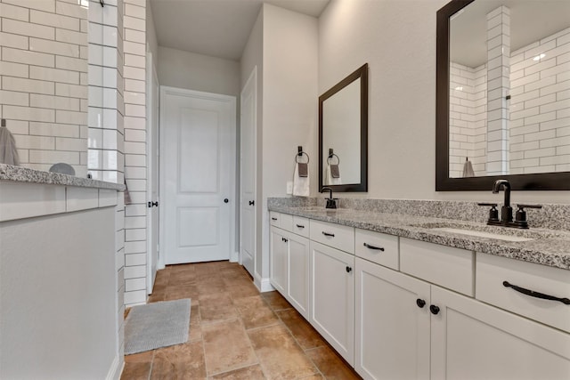 full bathroom with double vanity, a tile shower, and a sink