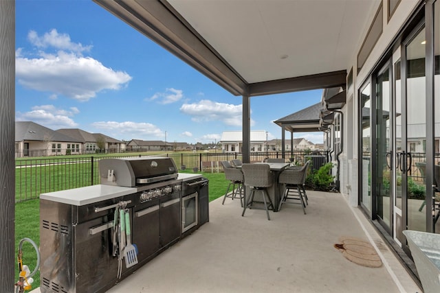 view of patio featuring outdoor dining space, a fenced backyard, a residential view, and an outdoor kitchen