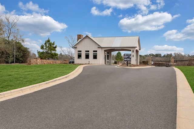 modern farmhouse style home featuring driveway, board and batten siding, a chimney, and a front lawn