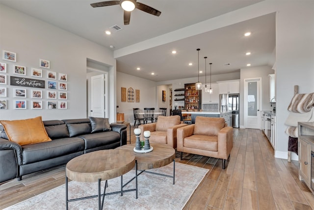 living area with recessed lighting, baseboards, light wood-type flooring, and a ceiling fan