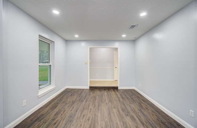 spare room featuring recessed lighting, dark wood finished floors, and baseboards