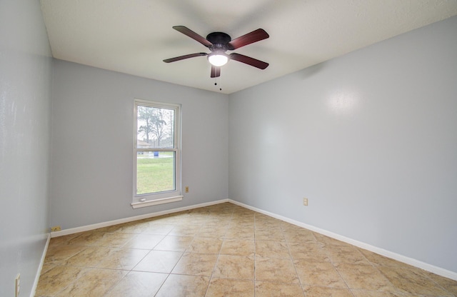 tiled empty room with ceiling fan and baseboards