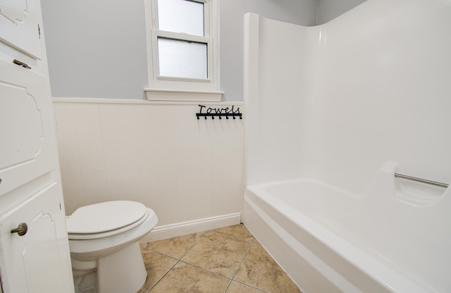 bathroom featuring toilet, tile patterned flooring, and wainscoting