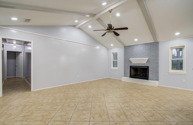 unfurnished living room with vaulted ceiling with beams, a fireplace, visible vents, attic access, and ceiling fan