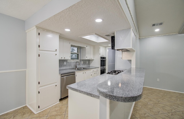 kitchen featuring stainless steel appliances, visible vents, white cabinetry, a sink, and a peninsula