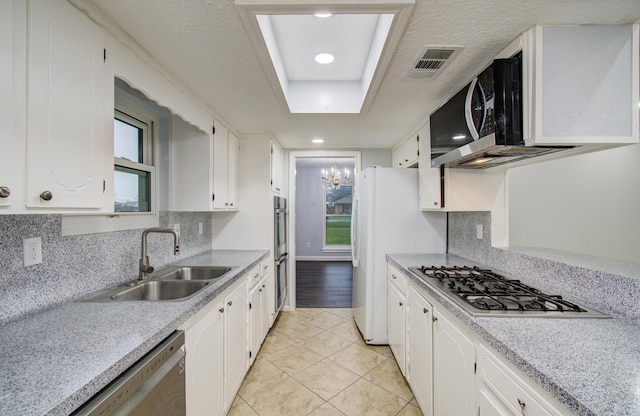 kitchen featuring appliances with stainless steel finishes, white cabinets, visible vents, and a sink