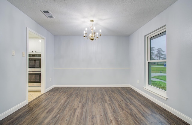 spare room with a healthy amount of sunlight, baseboards, visible vents, and wood finished floors